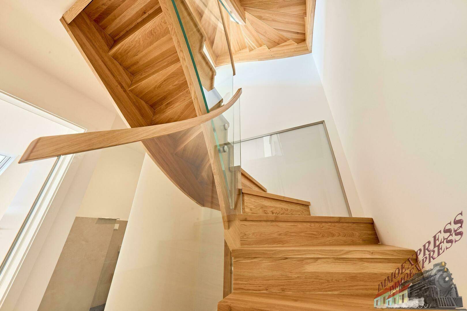 Elegante Holztreppe mit Glasgeländer, die zu den oberen Etagen der Wohnung führt.