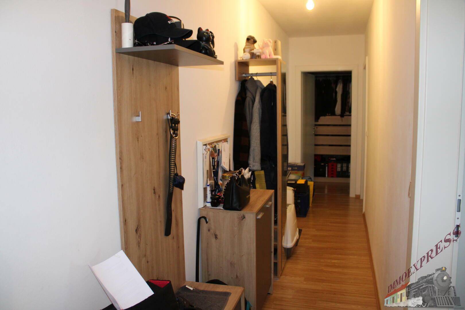 Heller Flur mit Garderobe und Zugang zu einem begehbaren Kleiderschrank.