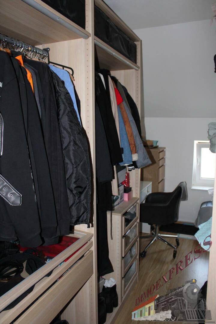 Geräumiger begehbarer Kleiderschrank im Dachgeschoss mit Fenster und Schreibtisch.