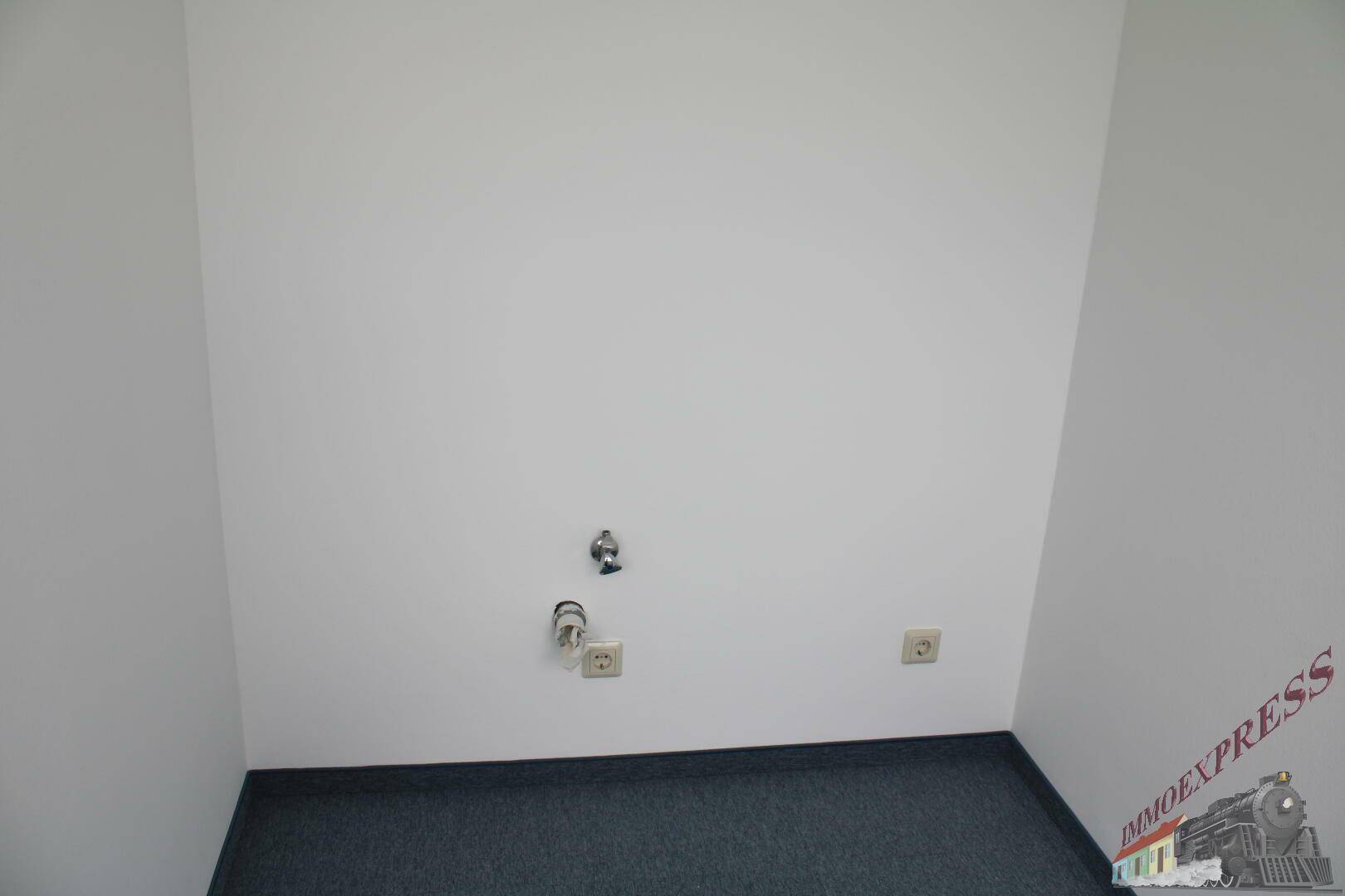 Eine leere Ecke mit Anschlüssen für Wasser und Strom, ideal für eine kleine Küchenzeile oder einen Abstellraum.
