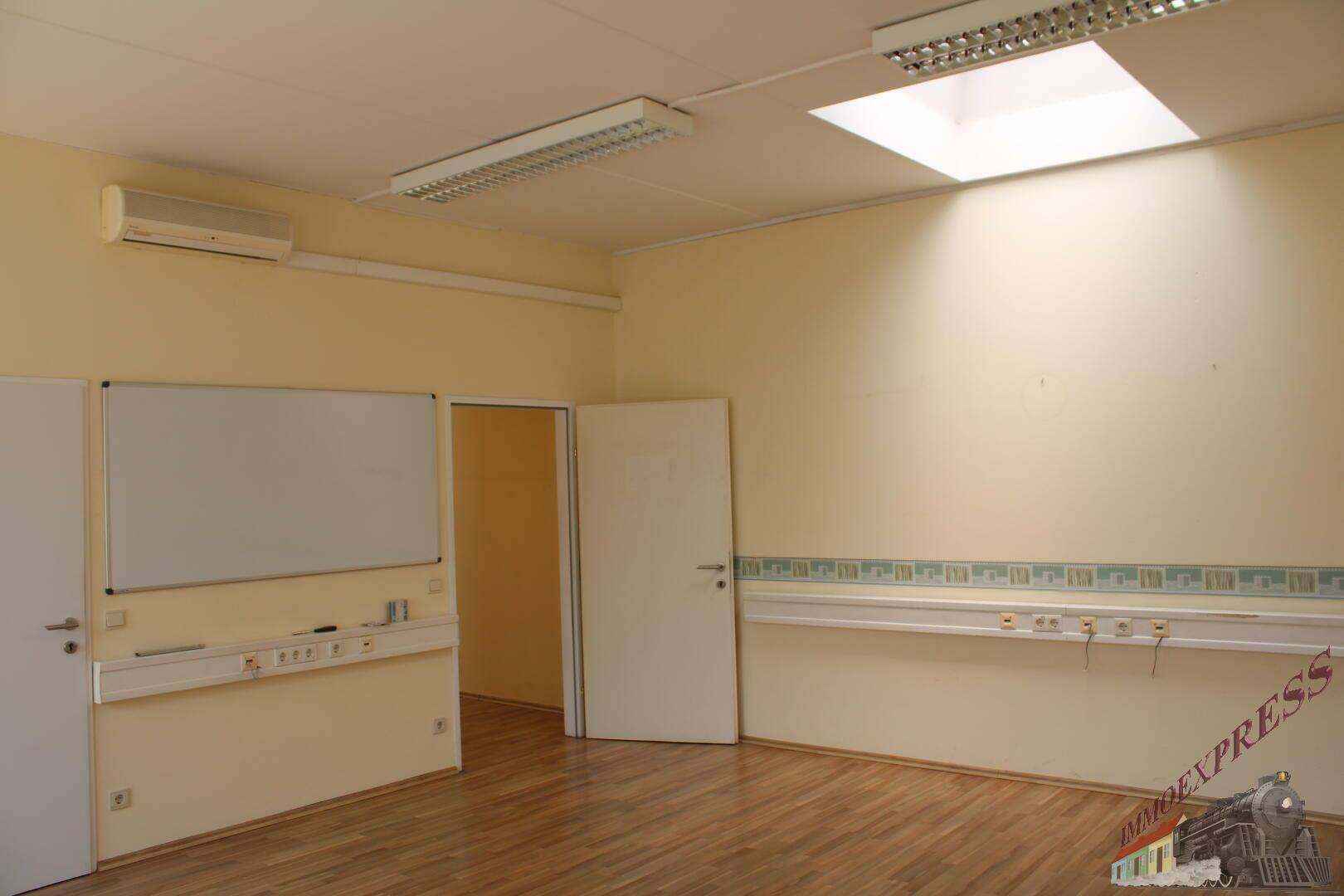 Helles Büro mit Holzboden, Deckenfenster und einer Klimaanlage an der Wand.