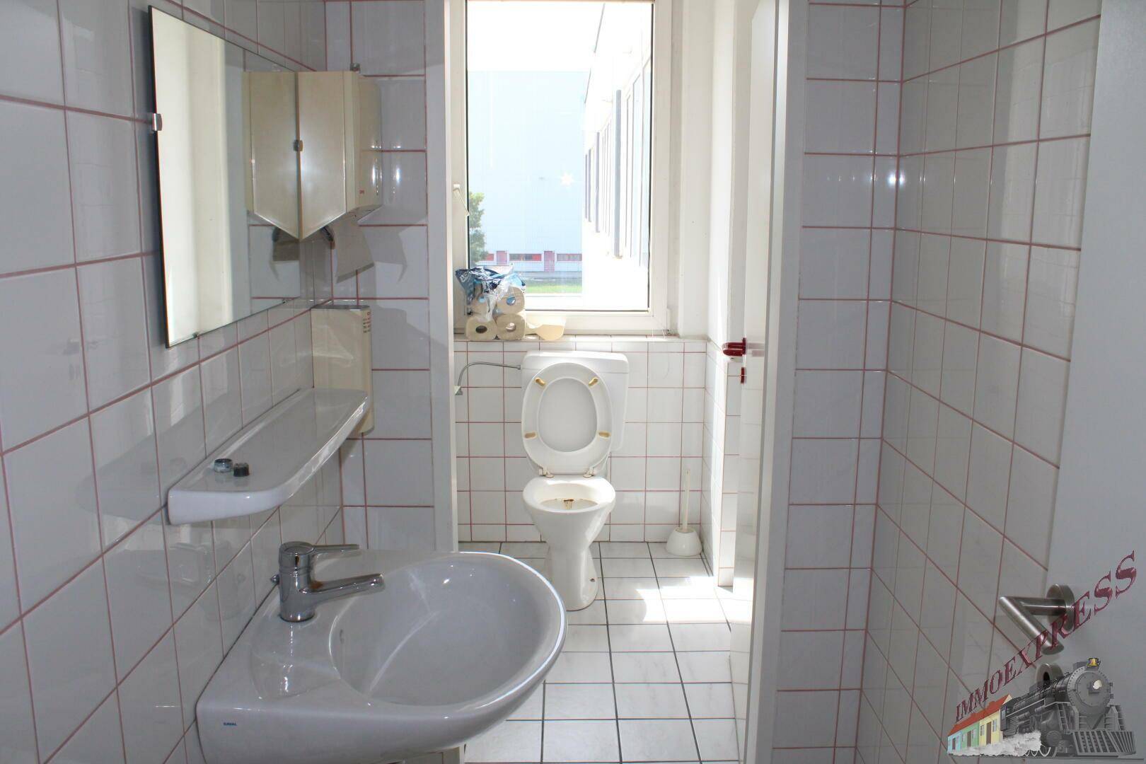 Toilettenraum mit Fenster, Waschbecken und weiß gefliesten Wänden.