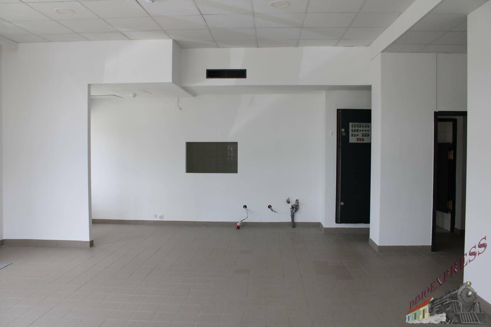 Großer, offener Gewerberaum mit Fliesenboden und sichtbaren Anschlüssen für eine mögliche Küchenzeile.