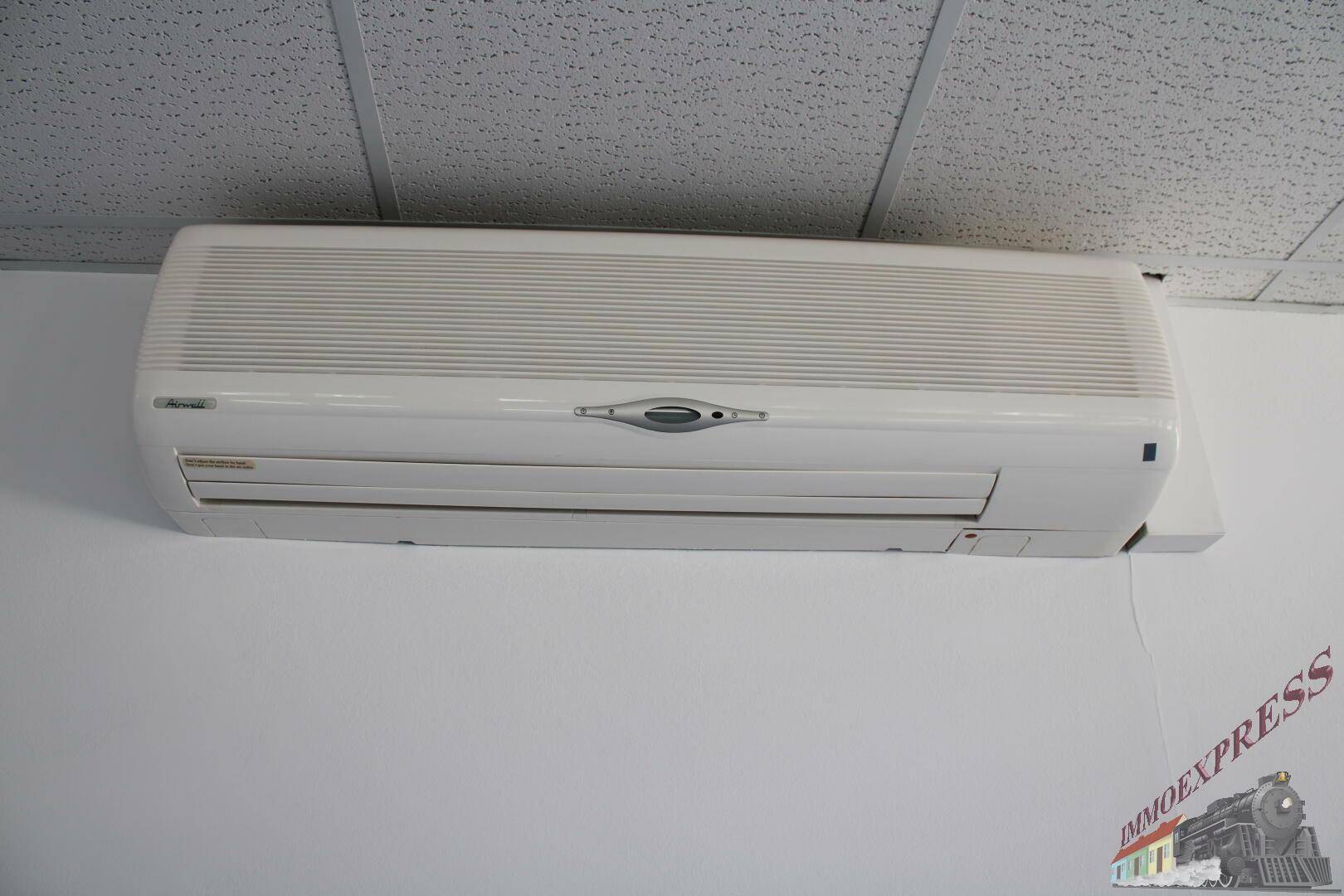 Eine an der Wand montierte Klimaanlage unter einer Rasterdecke.