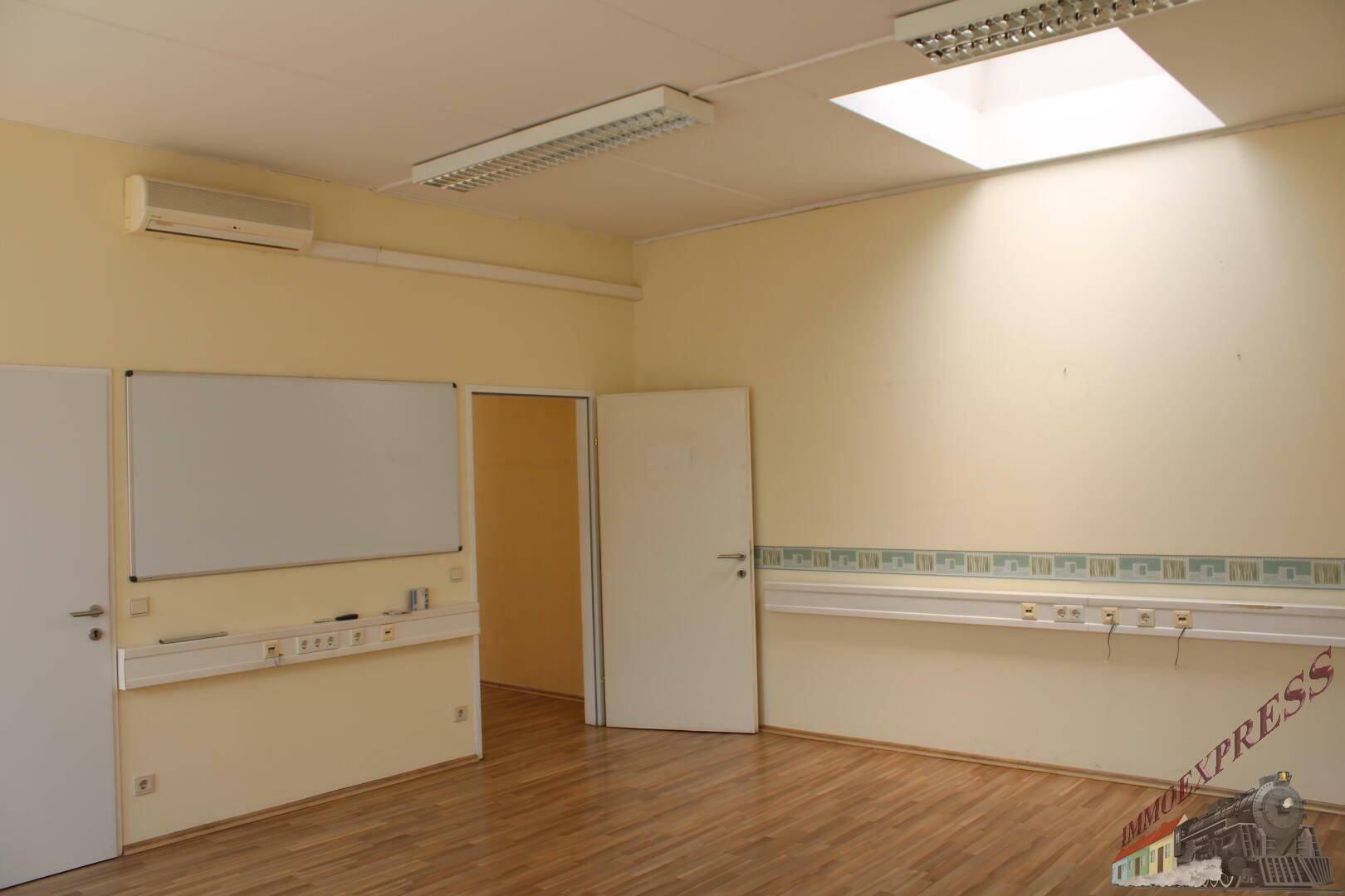 Geräumiges Büro mit Holzfußboden, Deckenbeleuchtung und einer Klimaanlage, bereit zur Nutzung.