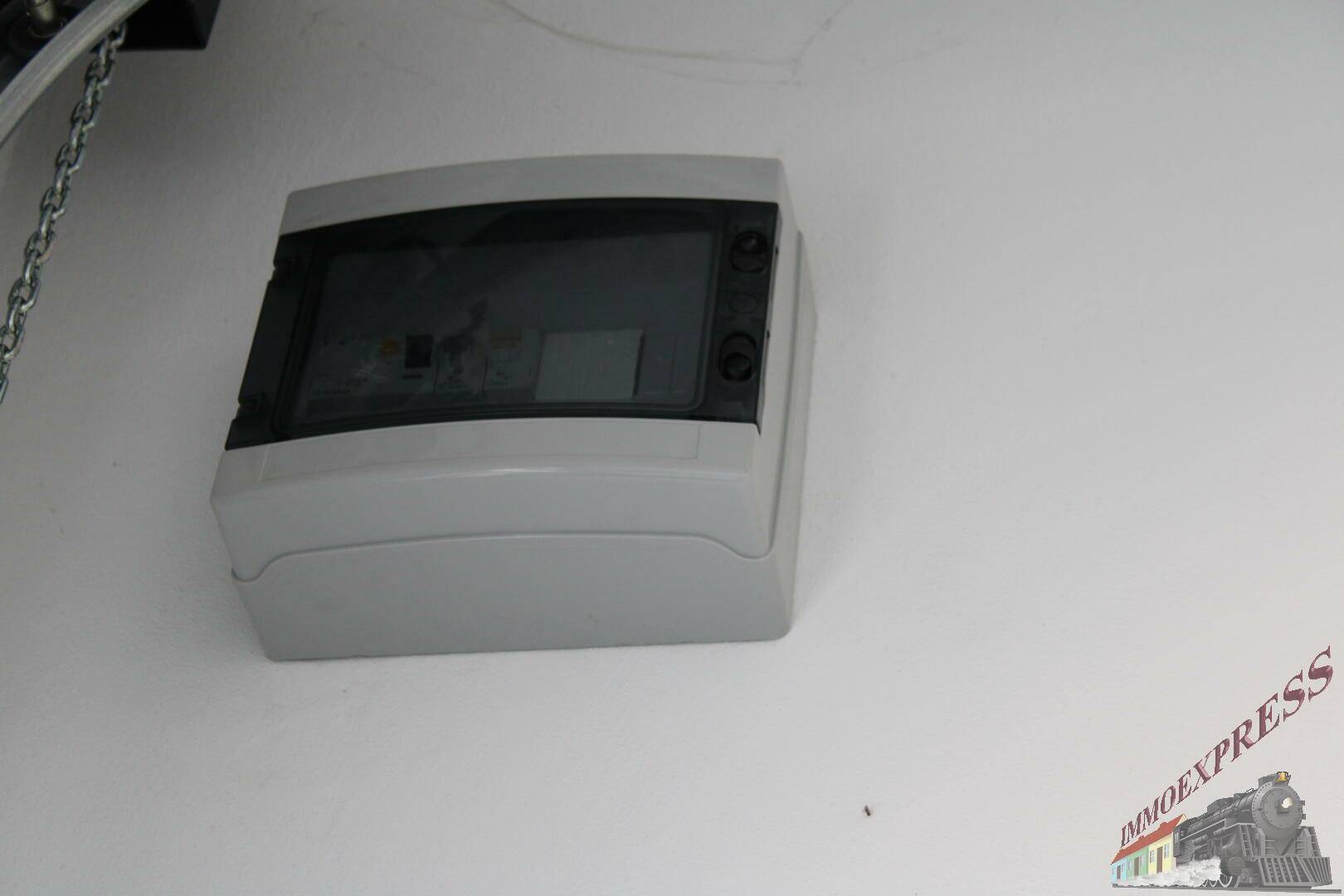 Nahaufnahme eines grauen Sicherungskastens an einer weißen Wand im Innenbereich.