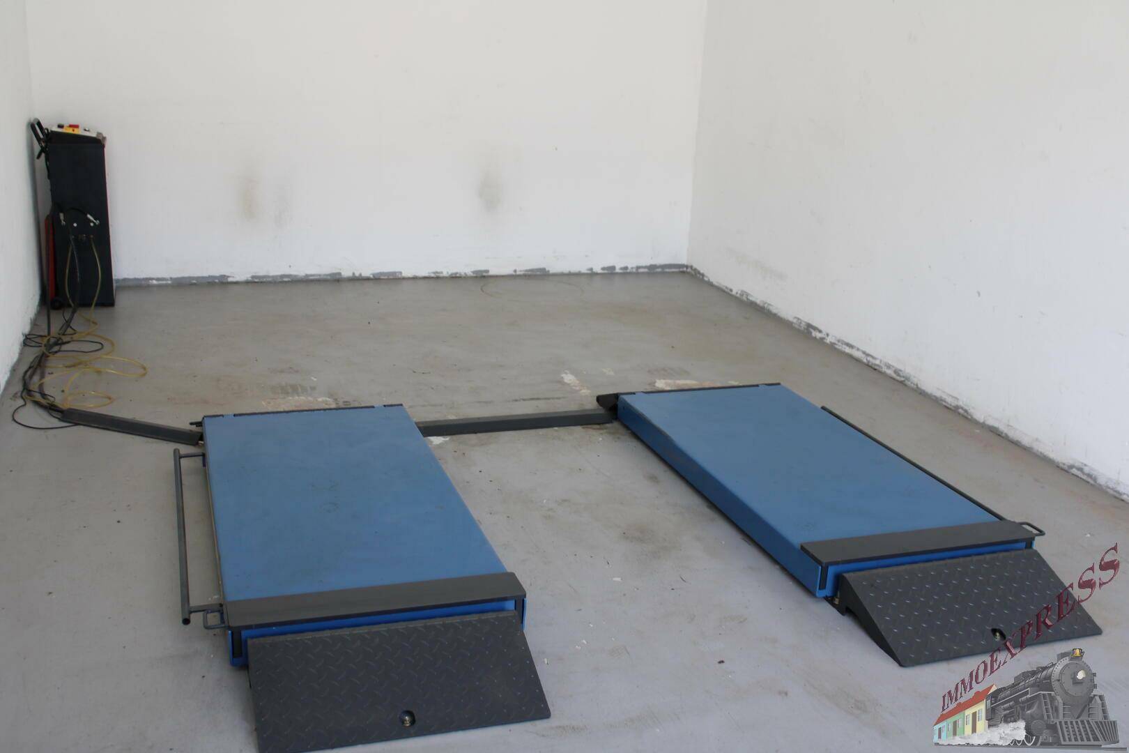 Detailansicht von zwei blauen Fahrzeugrampen auf dem Betonboden einer hellen Garagenbox.