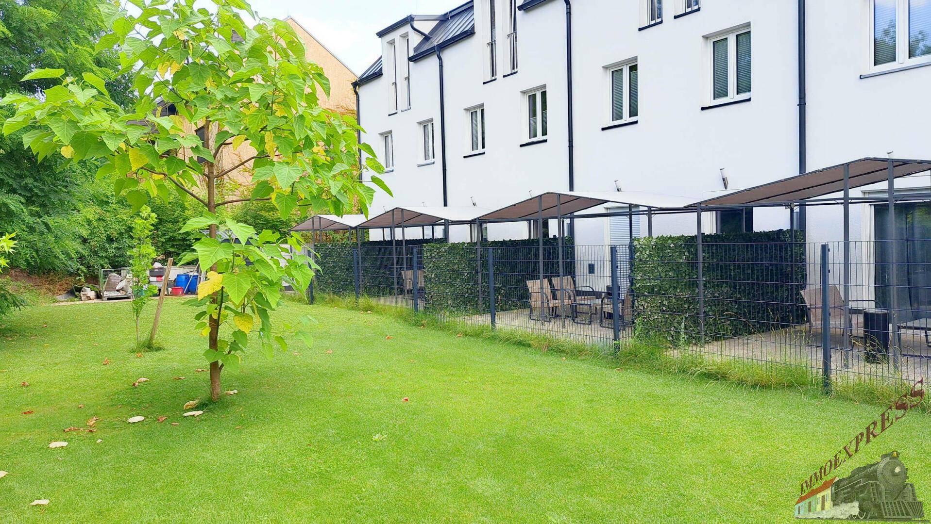 Grüner Garten mit Bäumen und überdachten Terrassen, die zum Entspannen einladen.