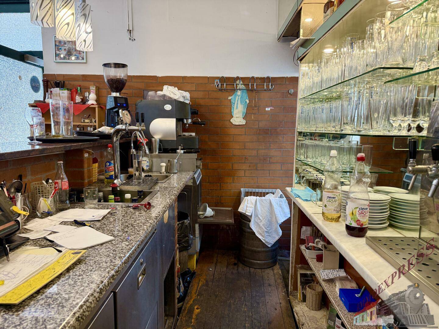 Gut ausgestatteter Barbereich mit Granit-Arbeitsplatte, Espressomaschine und Regalen voller Gläser und Flaschen.
