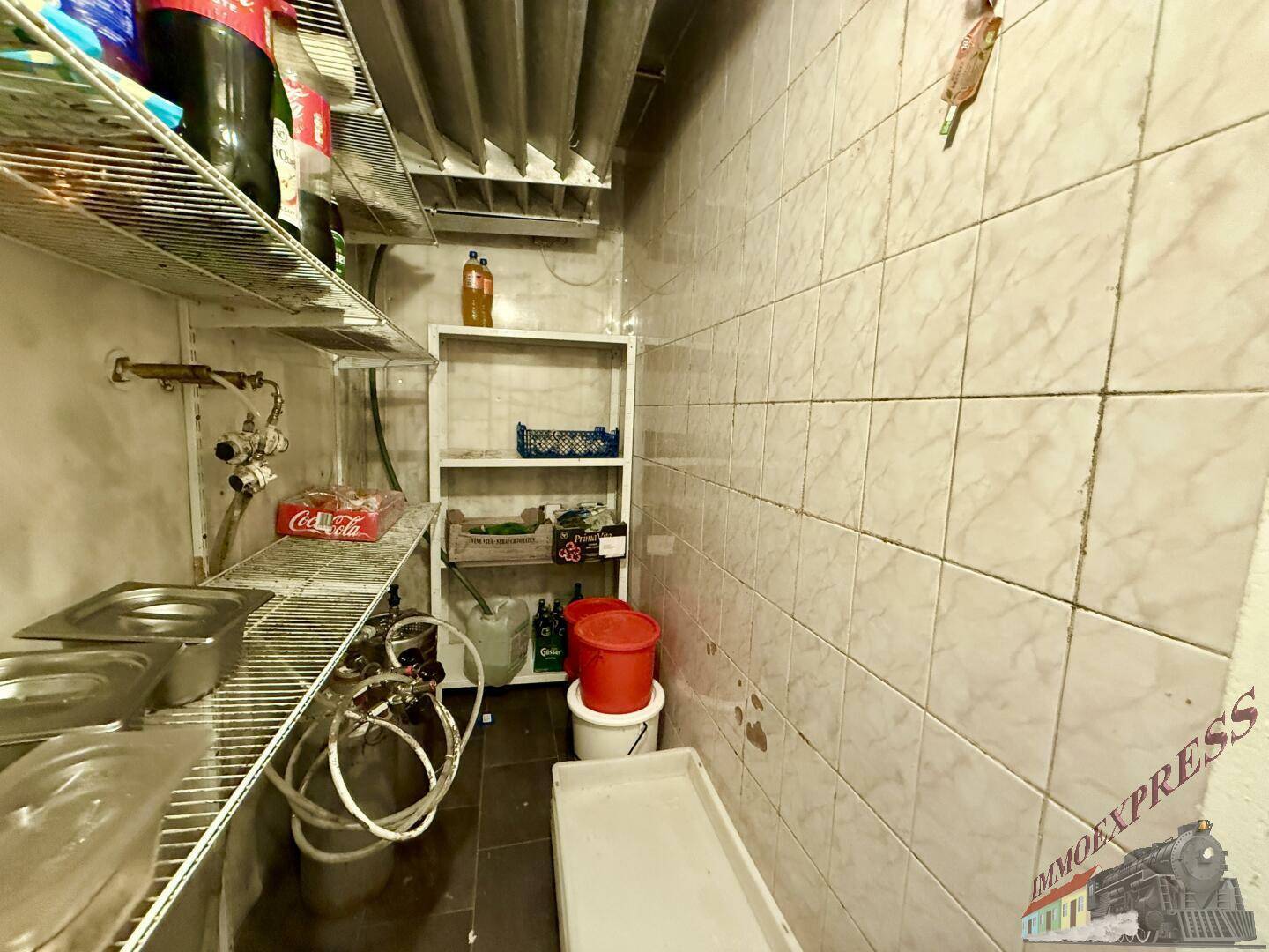 Kleiner Lagerraum in einer Restaurantküche mit Regalen, Vorräten und Fliesenwänden, optimiert für Effizienz.