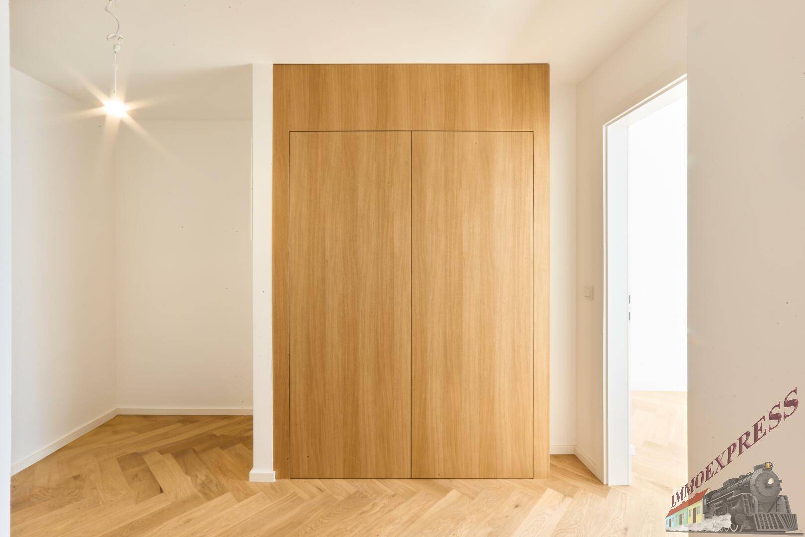Flur mit integrierten Holzschränken und Fischgrätparkett, bietet viel Stauraum.