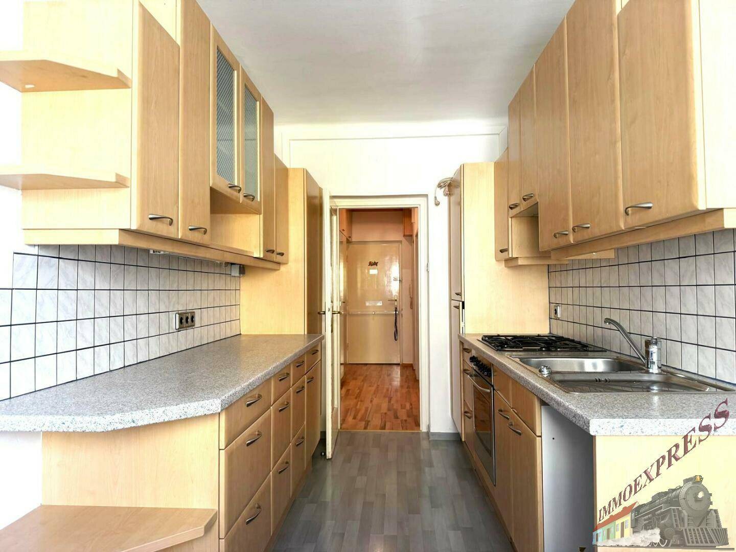 Funktionale Küche mit Holzschränken, Fliesenrückwand und integrierten Geräten.