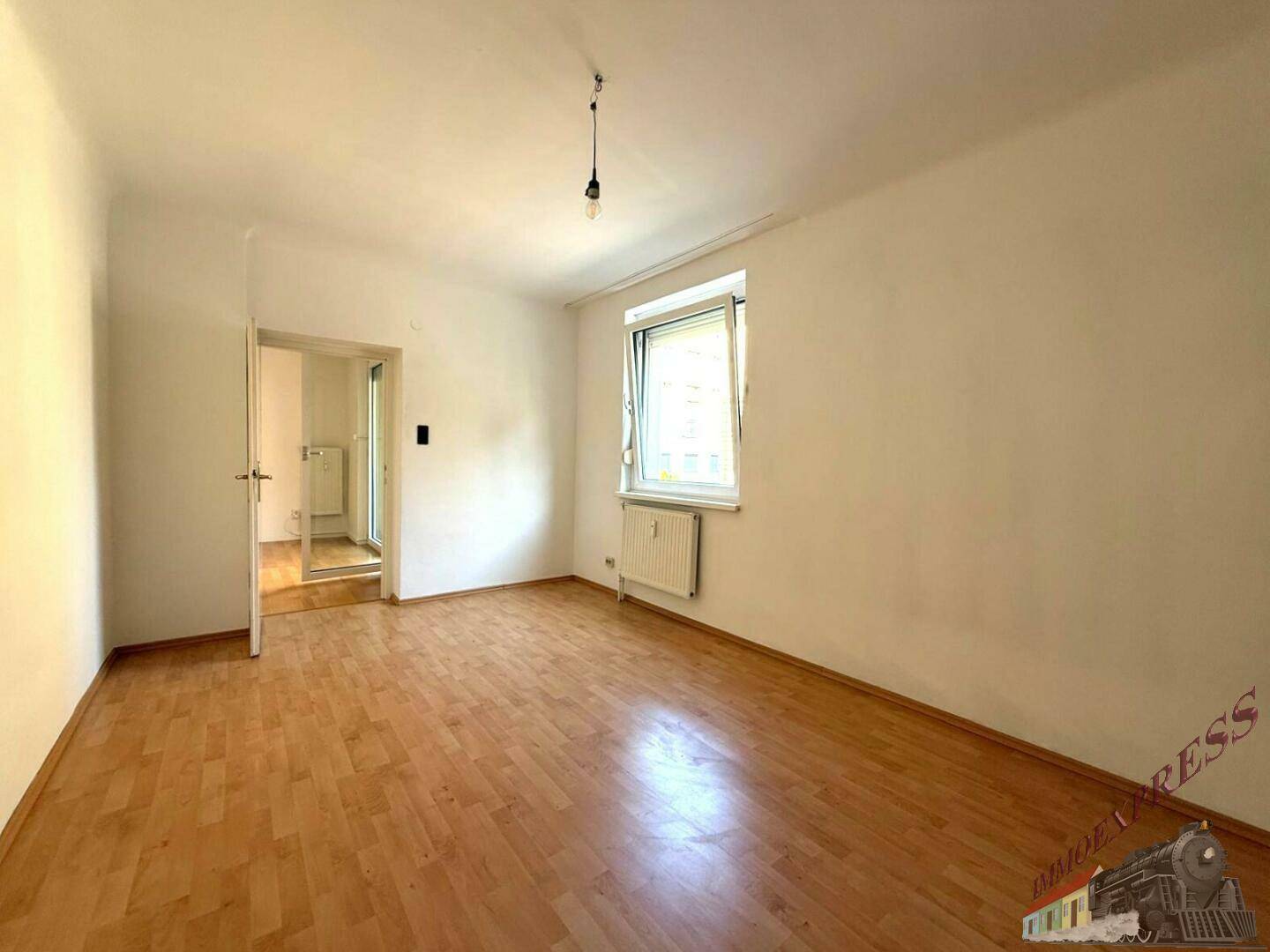 Geräumiges Zimmer mit Parkettboden und Fenster, das einen Blick auf die Umgebung ermöglicht.