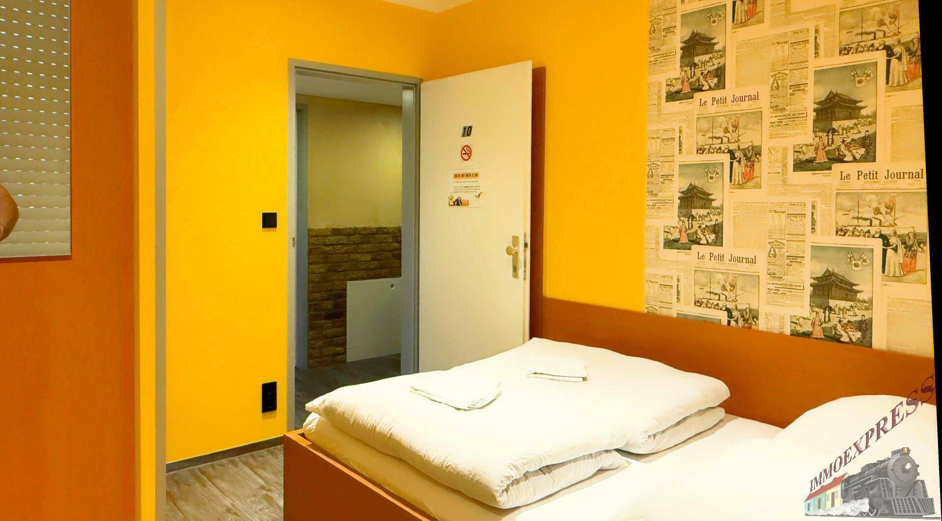 Helles Schlafzimmer mit gelben Wänden, einem Doppelbett und einer Tür, die zu einem weiteren Bereich führt.