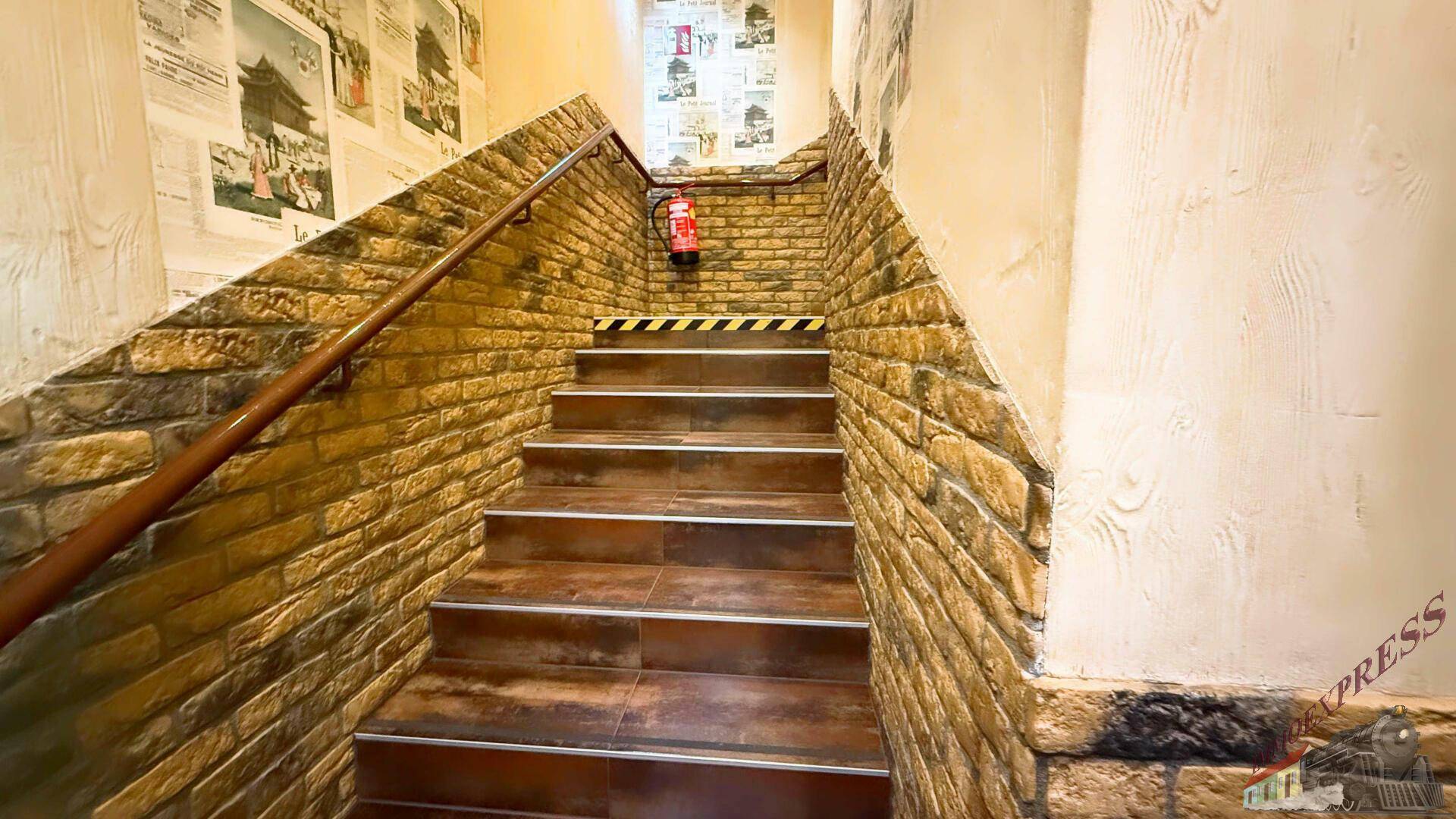 Treppenhaus mit Ziegelwandverkleidung und einem Holzgeländer, das zu den oberen Etagen führt.