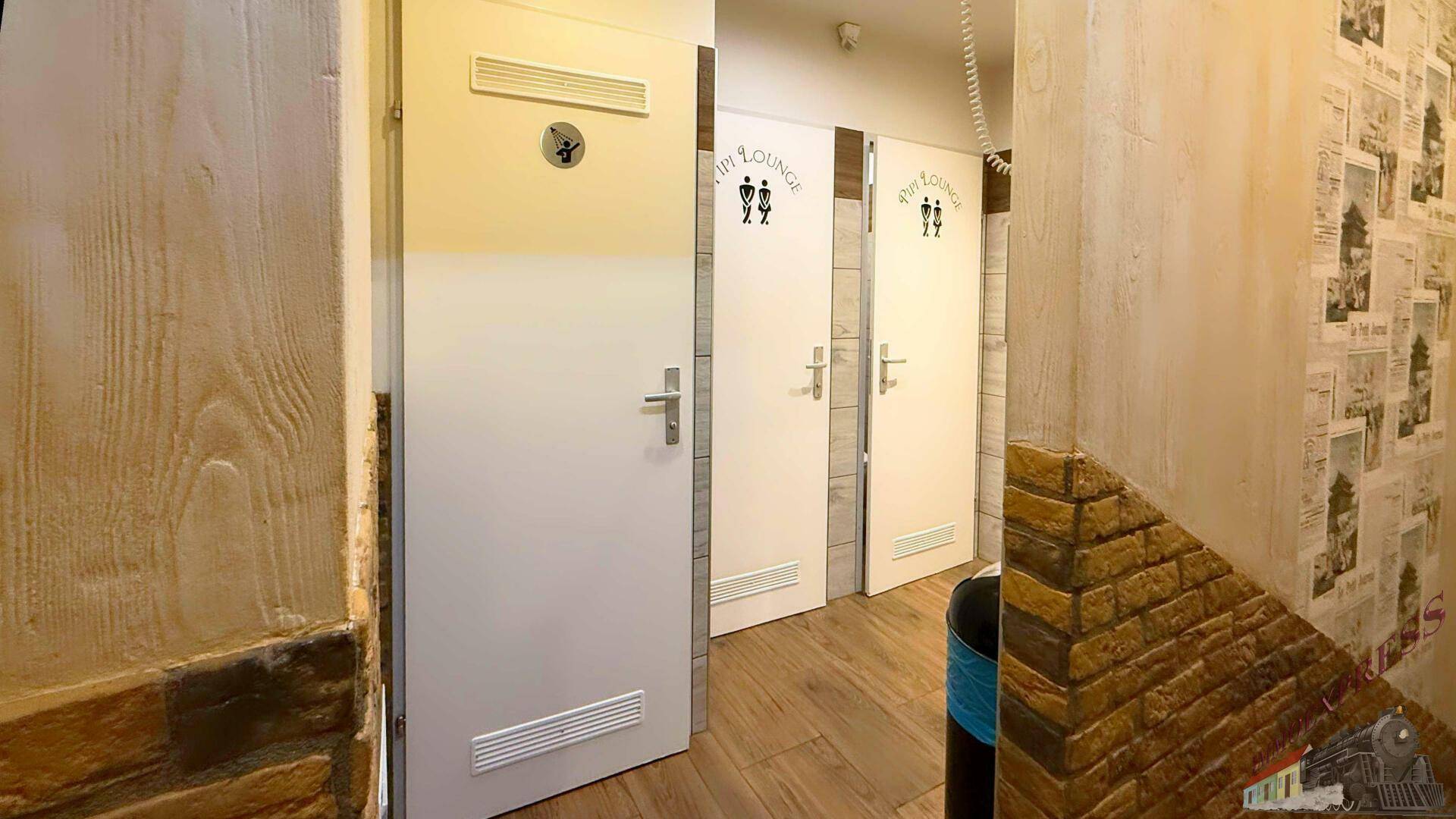Flur mit mehreren Türen zu Toiletten und Duschräumen, gekennzeichnet mit Piktogrammen für die Nutzung.