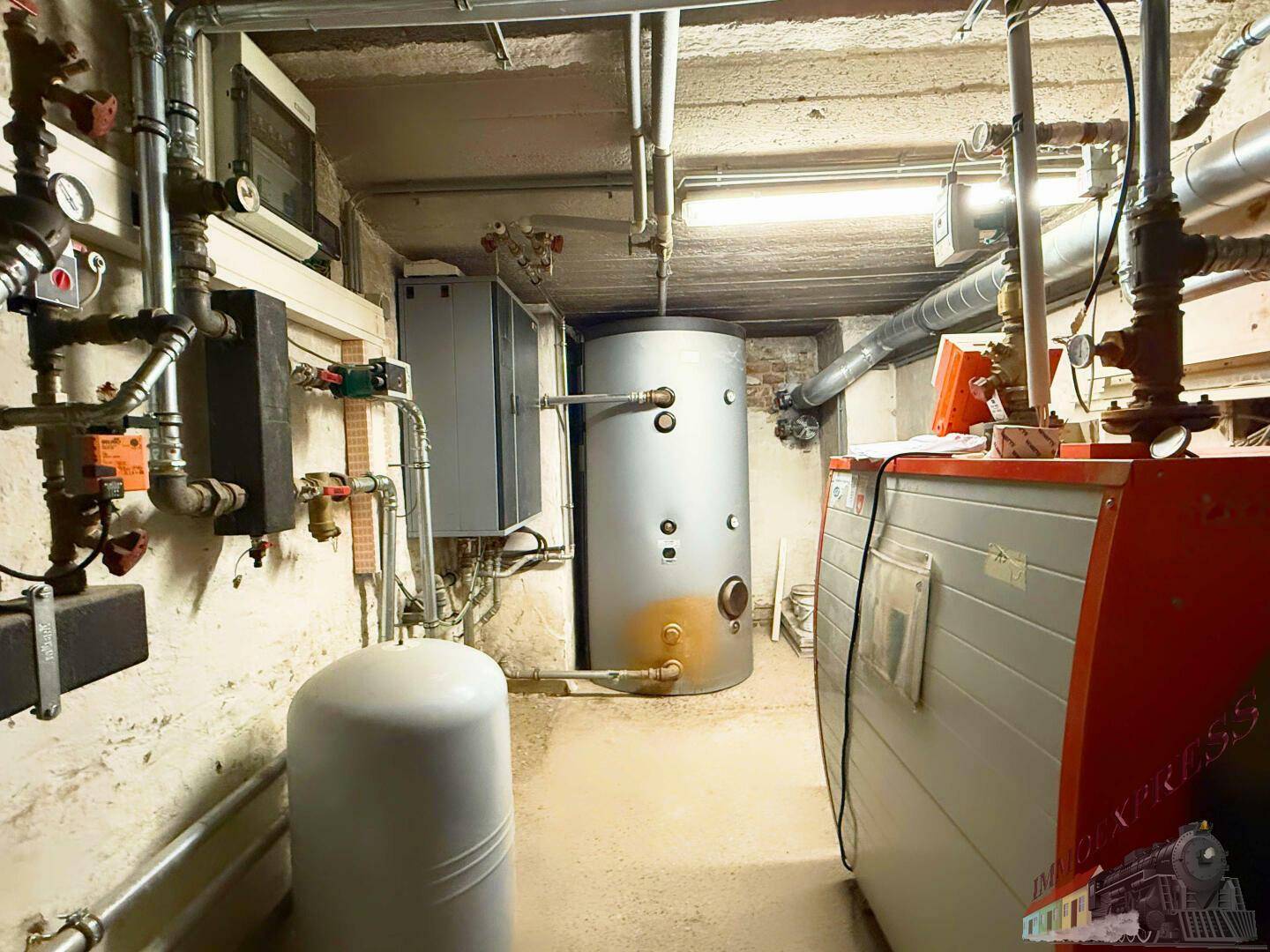 Heizungsraum mit Warmwasserspeicher und komplexen Rohrinstallationen, die die Wärmeversorgung des Gebäudes sicherstellen.