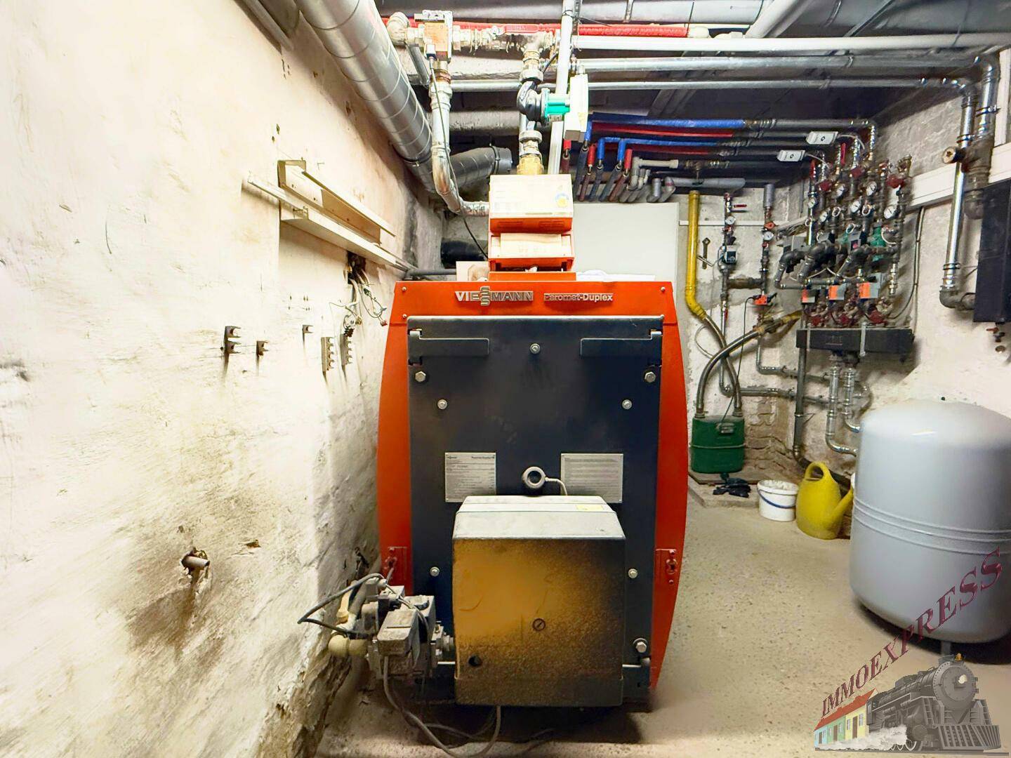 Heizungsraum mit einem großen Viessmann Heizkessel und zahlreichen Rohrleitungen an den Wänden.