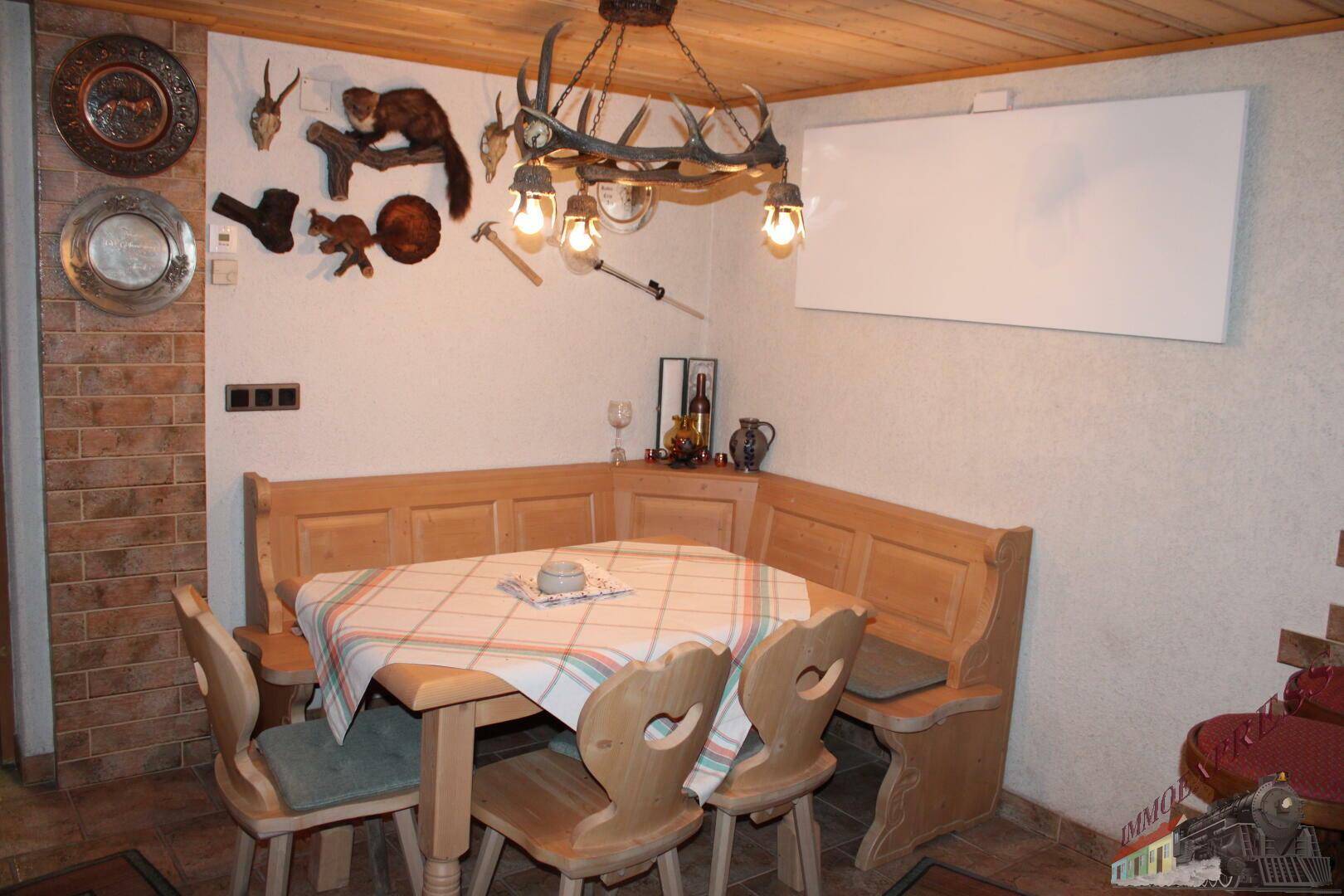 Rustikaler Essbereich mit Eckbank, Holztisch und Hirschgeweih-Dekoration.