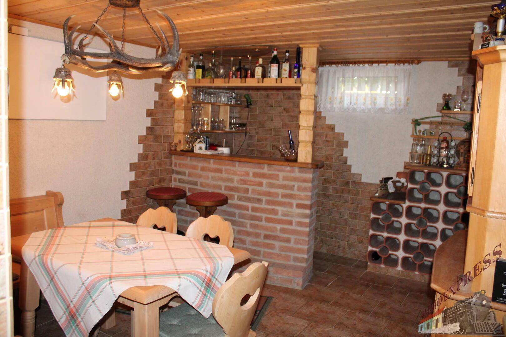 Rustikaler Partyraum im Keller mit Ziegelbar, Holztisch und Gewölbedecke.