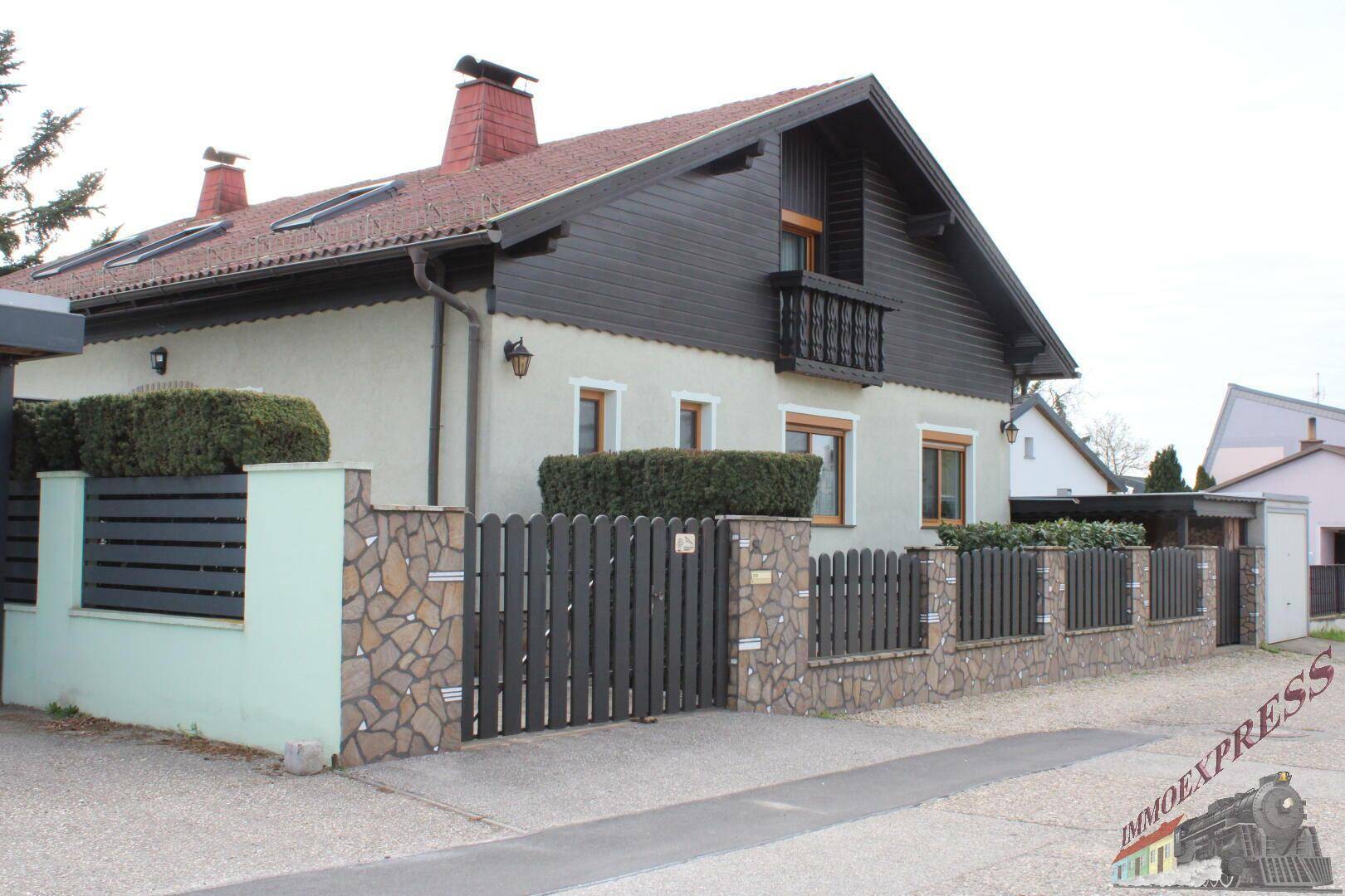 Ansicht des Hauses von der Straße mit gepflegtem Zaun und Vorgarten.
