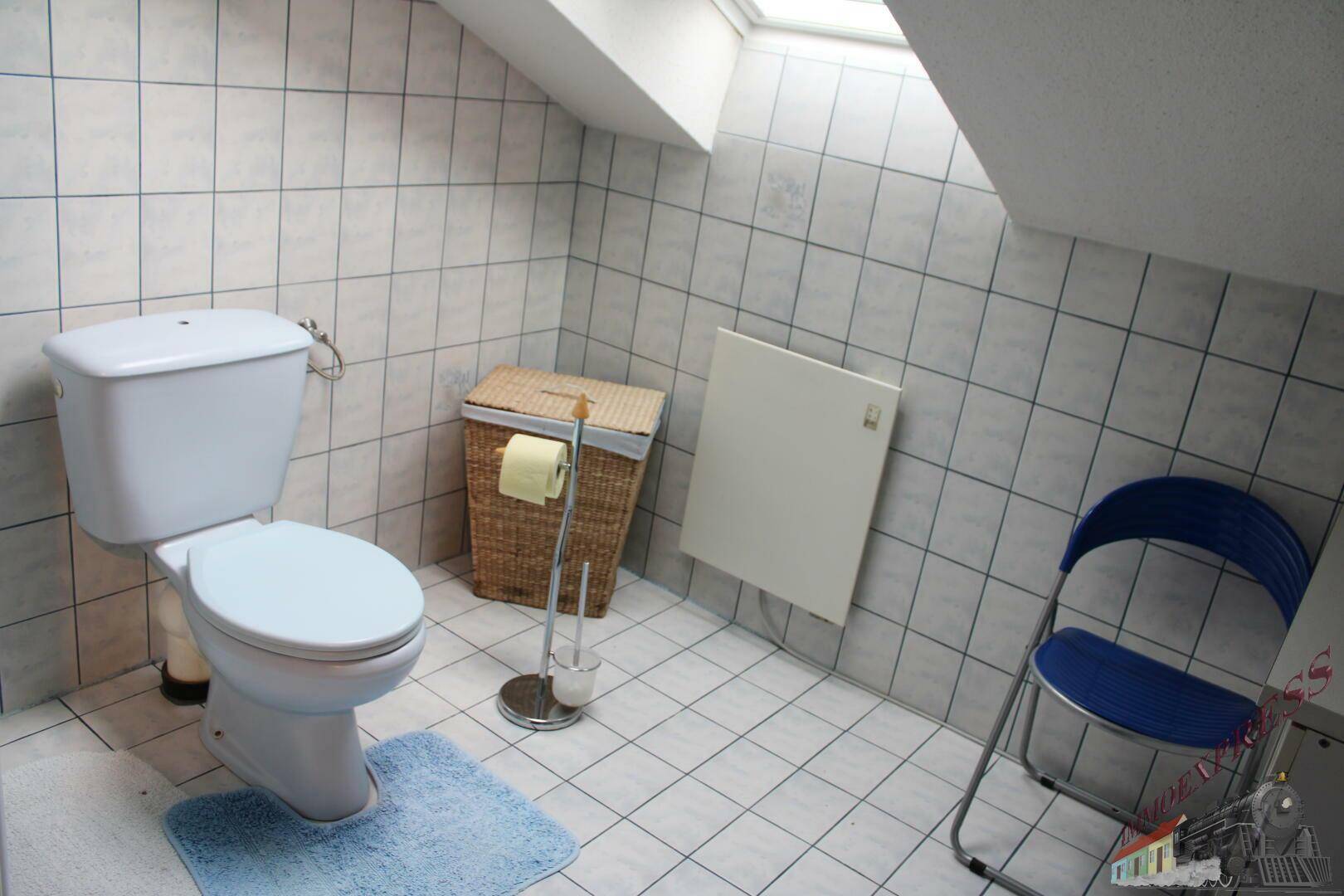 Kleines WC im Dachgeschoss mit weißen Fliesen und Dachfenster.
