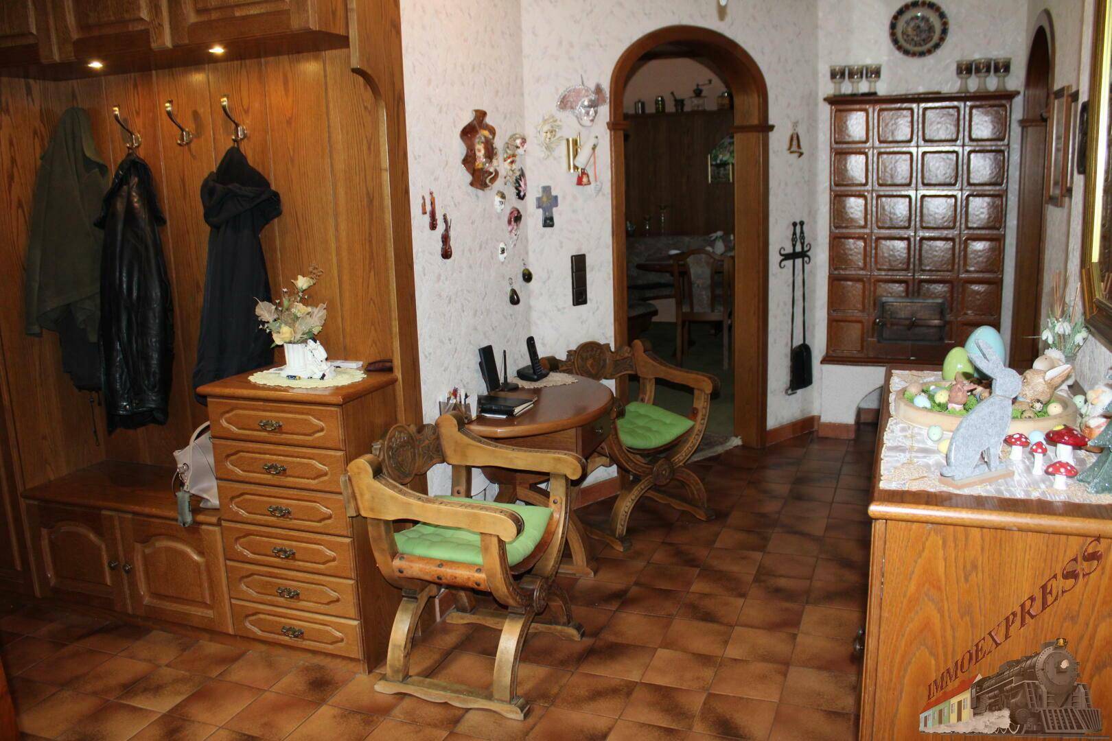 Eingangsbereich mit Holzgarderobe, Fliesenboden und traditioneller Dekoration.