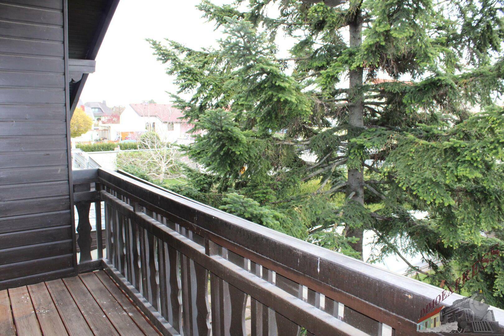 Holzbalkon mit Geländer und Blick auf die umliegende Nachbarschaft.