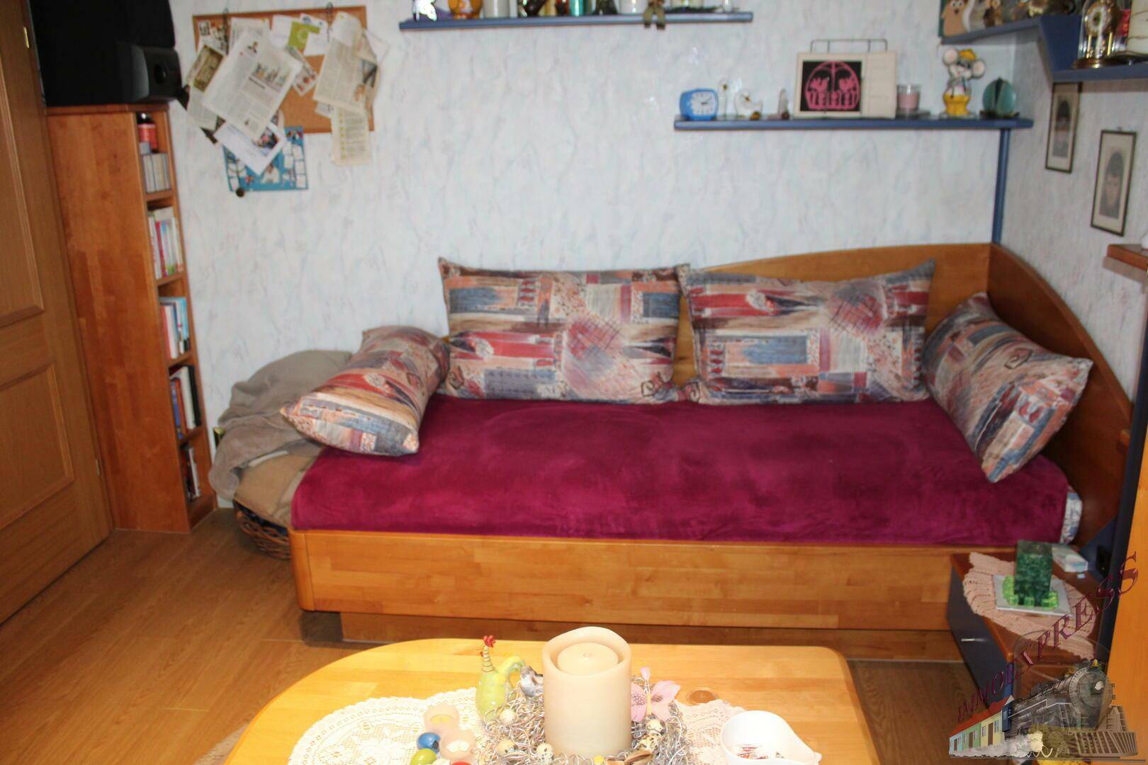 Gemütliches Zimmer mit Tagesbett, Holzboden und kleiner Sitzecke.