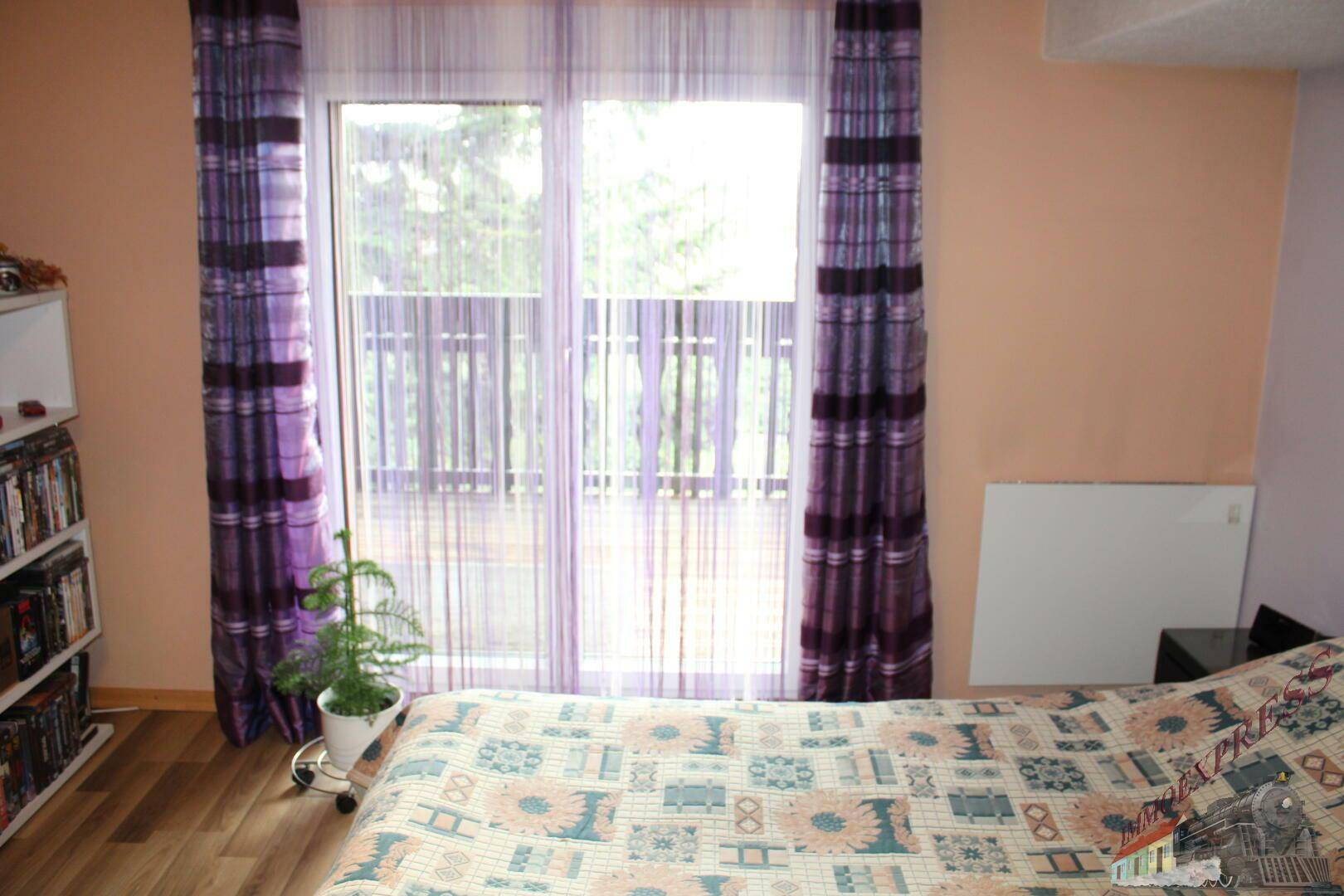 Schlafzimmer mit Doppelbett und großem Fenster mit Blick ins Grüne.
