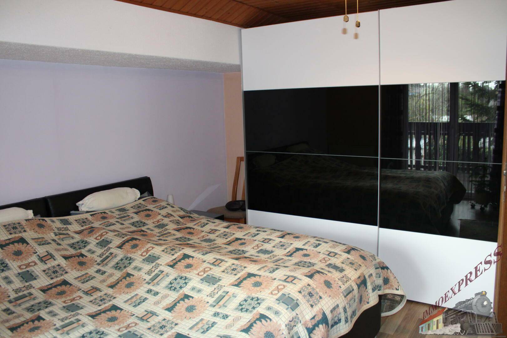 Schlafzimmer mit großem Kleiderschrank, Doppelbett und Holzboden.