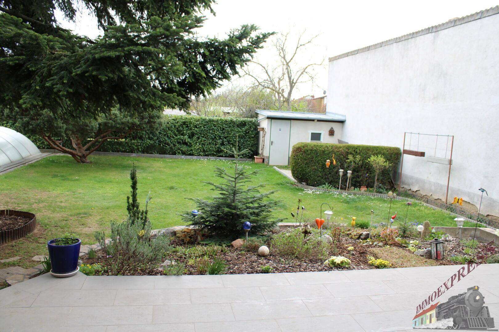 Großer, gepflegter Garten mit Rasenfläche, Blumenbeeten und einem Gartenschuppen.