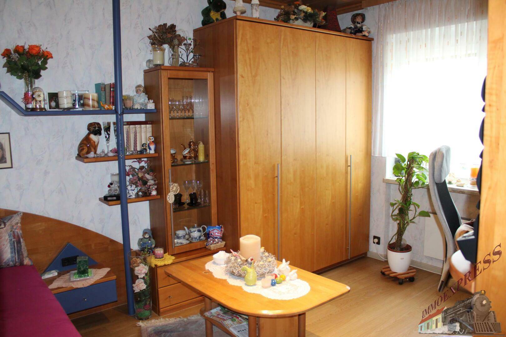 Kinderzimmer mit Holzschrank, Schreibtisch und Fenster mit viel Tageslicht.