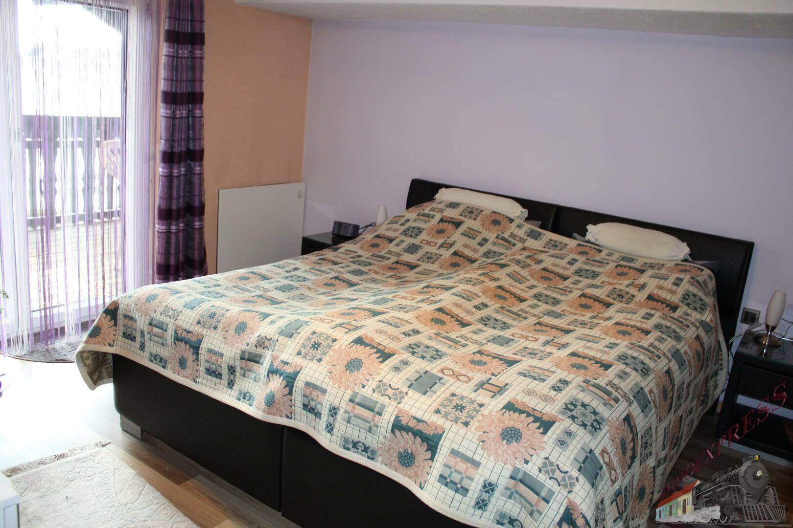Schlafzimmer mit Doppelbett, Holzboden und Zugang zu einem Balkon.