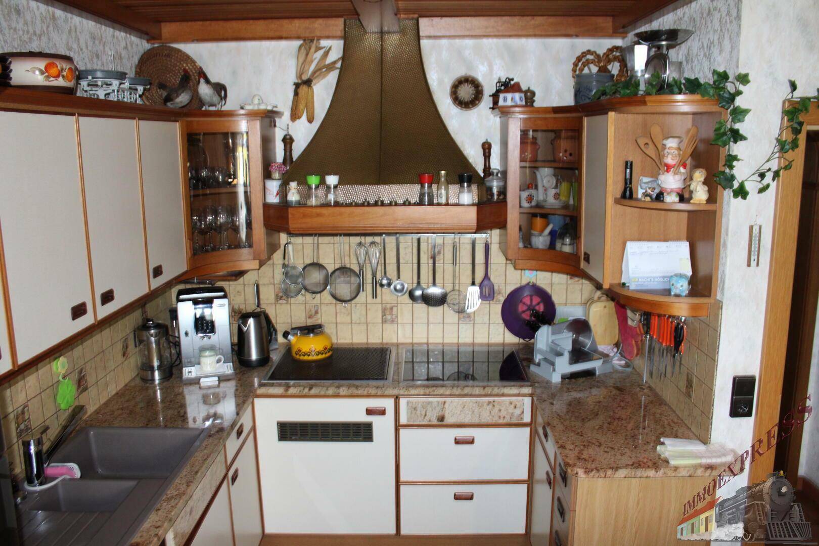 Funktionale Küche mit Holzschränken, Granitarbeitsplatten und integrierten Kochfeldern.