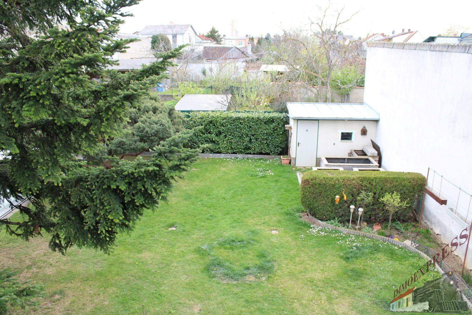 Weitläufiger Gartenbereich mit Rasenfläche, Hecken und einem Gartenschuppen.