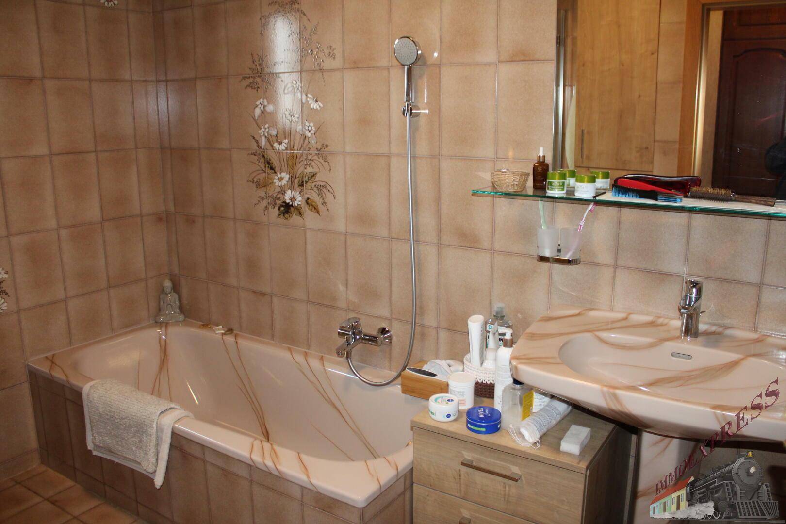 Badezimmer mit Badewanne, Waschbecken und beigefarbenen Fliesen.