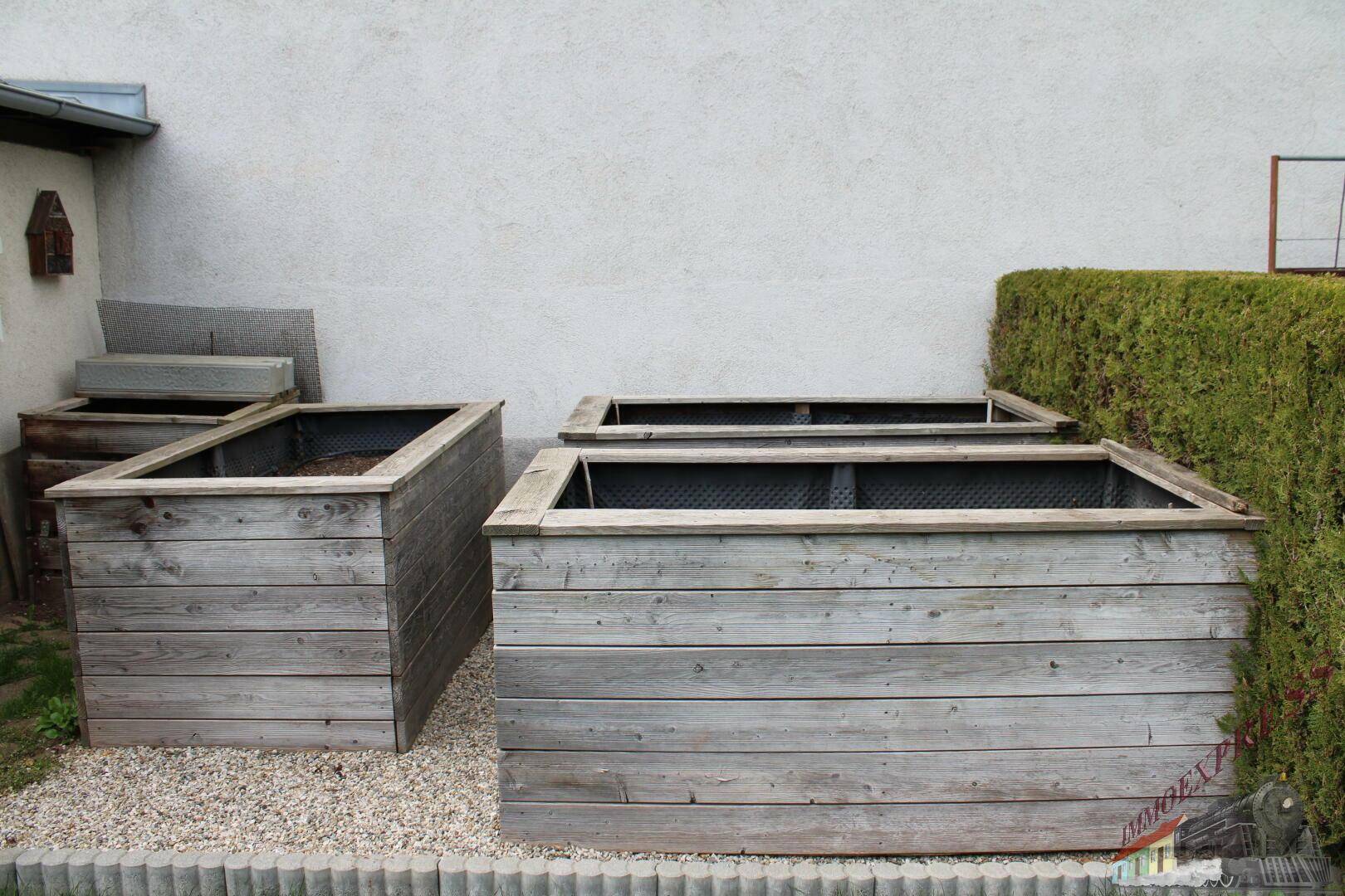 Erhöhte Hochbeete aus Holz im Gartenbereich, bereit für die Bepflanzung.