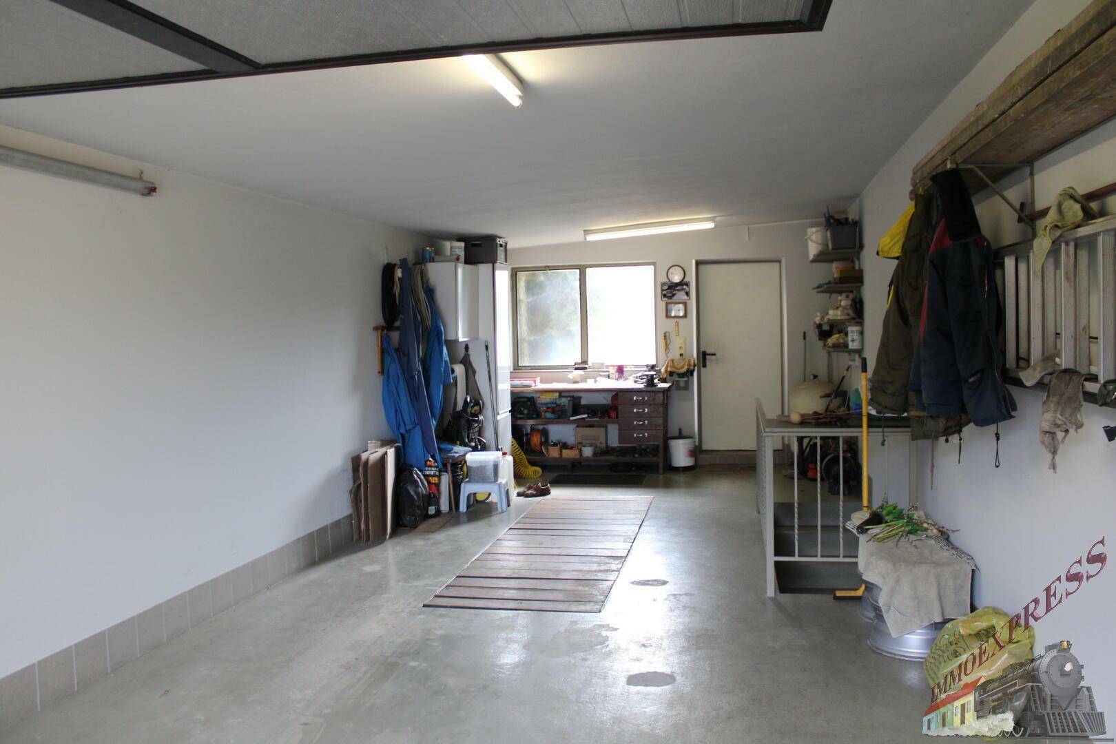 Geräumige Garage mit Werkstattbereich, Fenster und viel Stauraum.