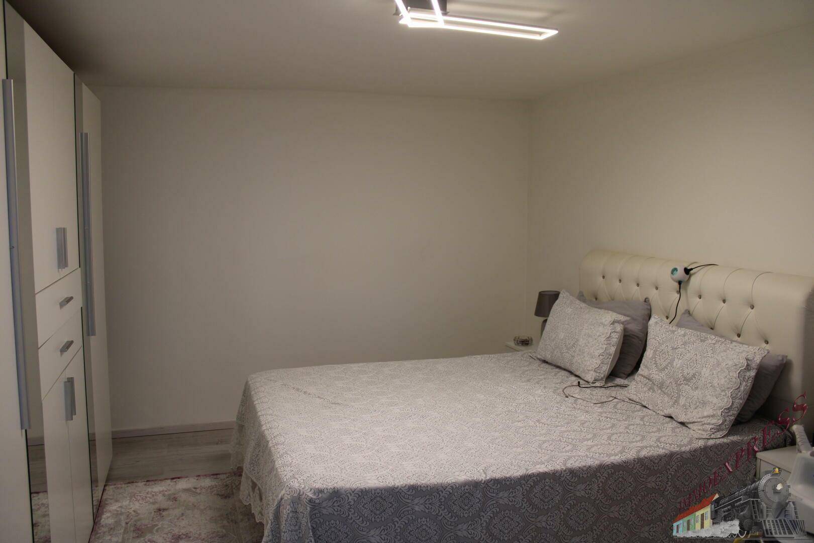 Schlafzimmer mit Doppelbett und weißem Kleiderschrank, schlicht und funktional eingerichtet.