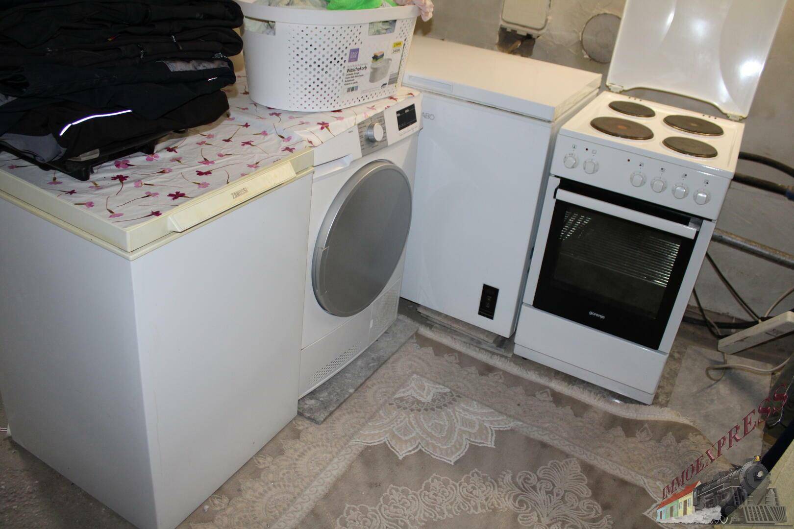 Hauswirtschaftsraum mit Waschmaschine, Trockner, Gefriertruhe und Herd.