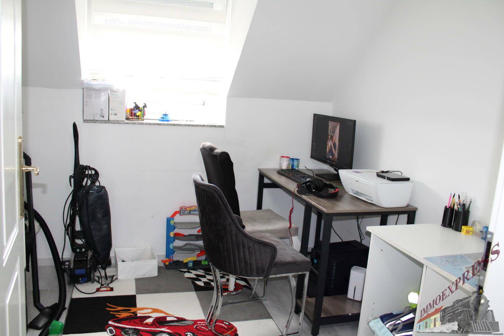 Helles Arbeitszimmer im Dachgeschoss mit Schreibtisch, Computer und schräger Decke.