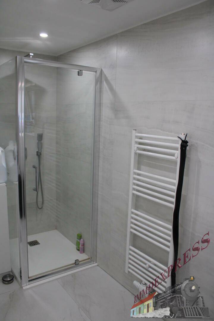 Modernes Badezimmer mit Duschkabine und beheiztem Handtuchhalter.