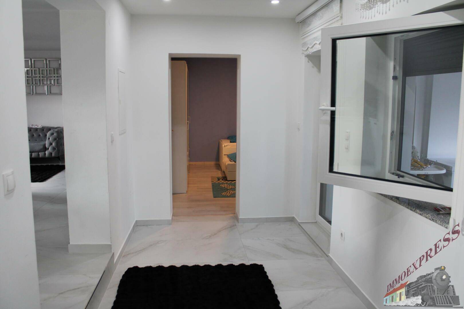 Heller Flur mit offenem Fenster und Zugang zu weiteren Räumen.