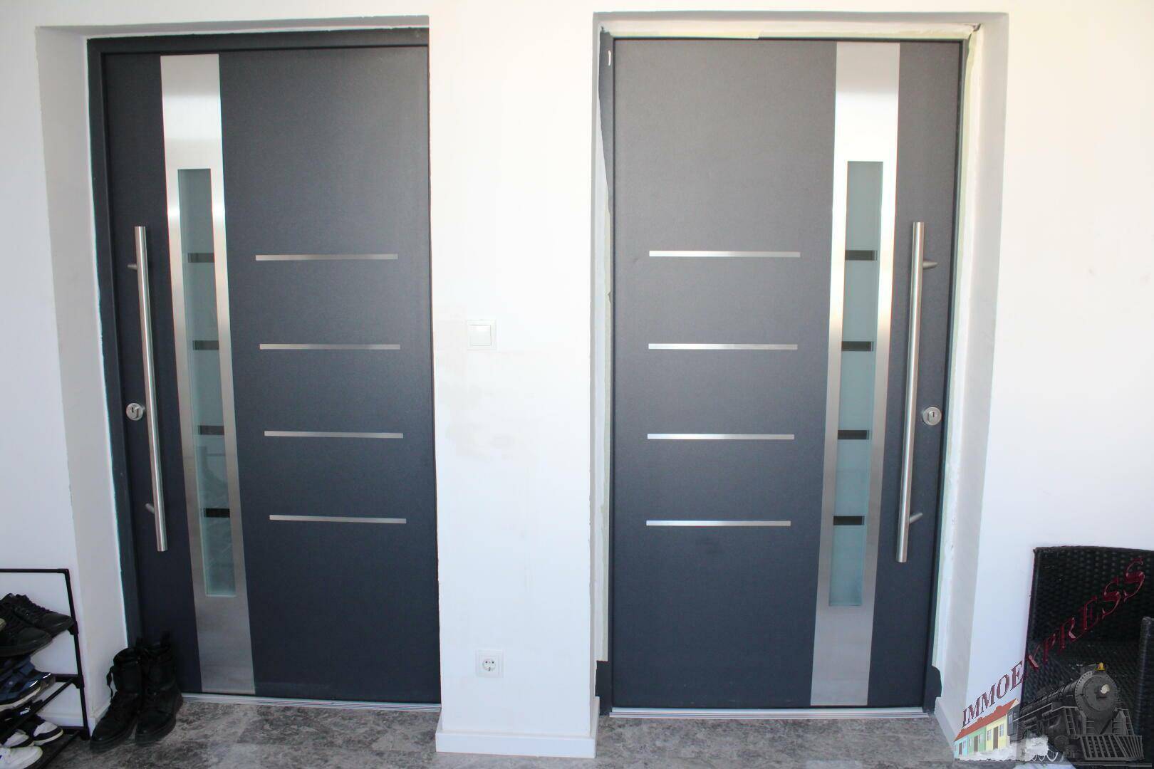 Zwei moderne Eingangstüren mit Glaseinsätzen und Edelstahlgriffen.