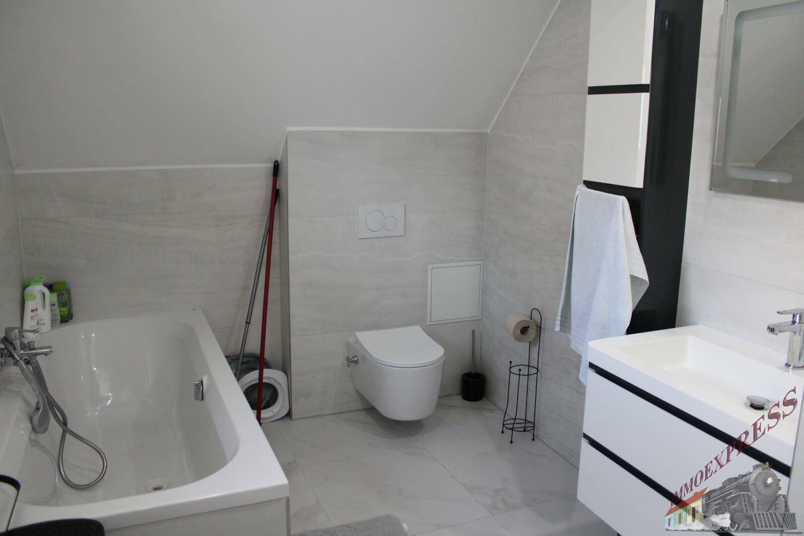 Modernes Badezimmer im Dachgeschoss mit Badewanne, wandhängendem WC und Waschtisch.