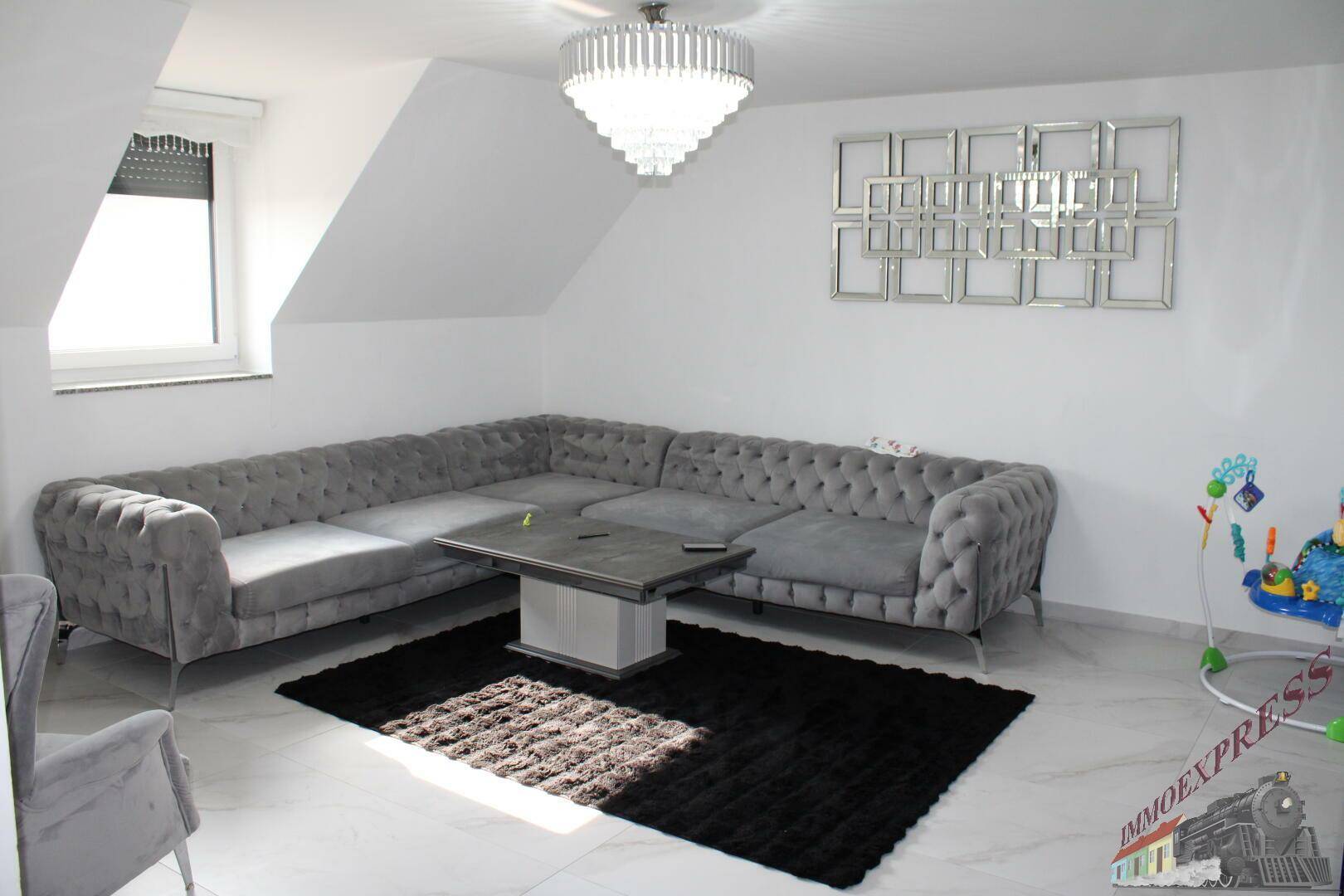 Gemütliches Wohnzimmer im Dachgeschoss mit schräger Decke und großem Ecksofa.