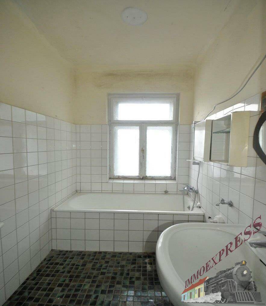 Badezimmer mit weiß gefliesten Wänden, Badewanne, Waschbecken und einem Fenster für Tageslicht.