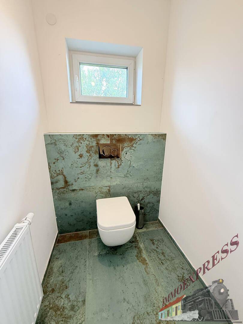 Modernes Gäste-WC mit wandhängender Toilette und auffälligen Fliesen, beleuchtet durch ein kleines Fenster.