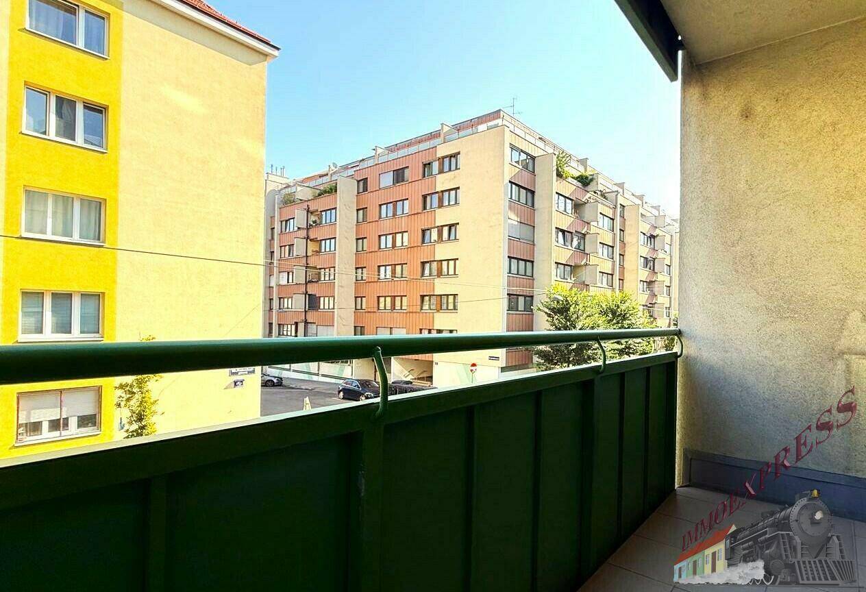 Balkon mit grüner Brüstung und Blick auf die umliegenden Wohngebäude in der Stadt.